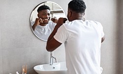 man flossing in front of the bathroom mirror