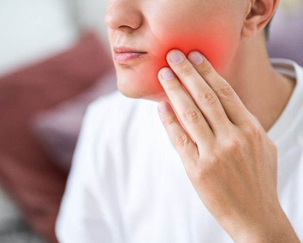 Young man holing his face with jaw pain 