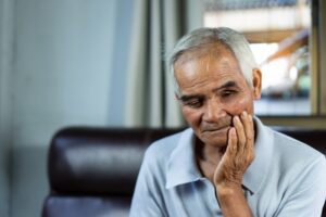 older man holding his face in concern